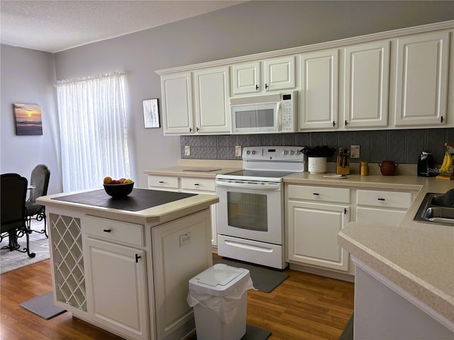 kitchen with white appliances, white cabinetry, light countertops, and wood finished floors