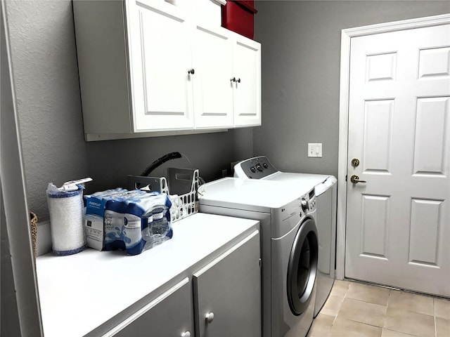 laundry room with cabinets, washing machine and dryer, and light tile patterned floors