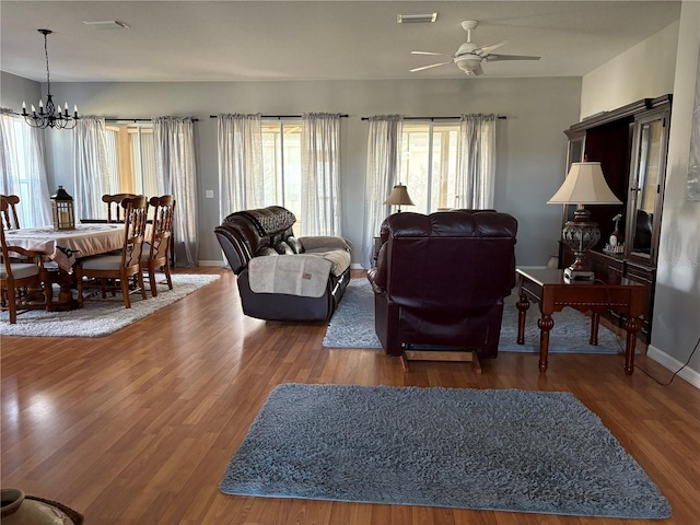 living room with baseboards, visible vents, wood finished floors, and ceiling fan with notable chandelier