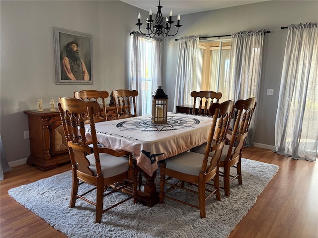 dining space featuring baseboards, a chandelier, and wood finished floors