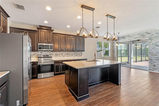 kitchen featuring visible vents, a sink, decorative backsplash, light countertops, and appliances with stainless steel finishes