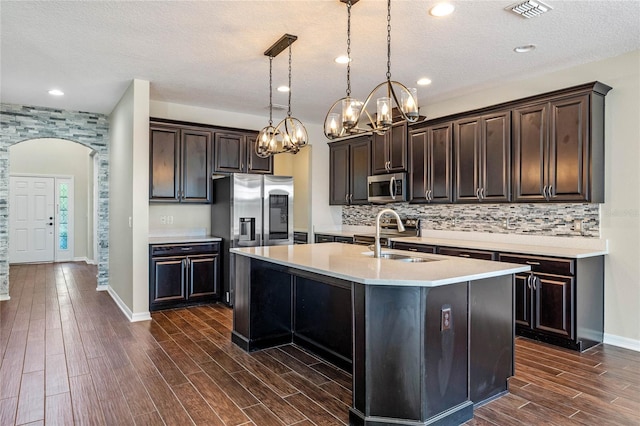 kitchen featuring visible vents, a sink, stainless steel appliances, arched walkways, and a chandelier