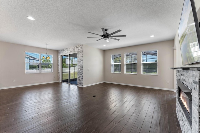 unfurnished living room featuring recessed lighting, dark wood-type flooring, a textured ceiling, a glass covered fireplace, and ceiling fan with notable chandelier