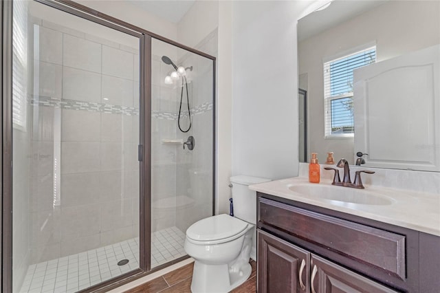 bathroom with wood finished floors, toilet, a stall shower, and vanity