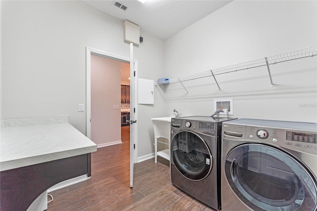 clothes washing area featuring visible vents, washing machine and dryer, dark wood-style floors, baseboards, and laundry area