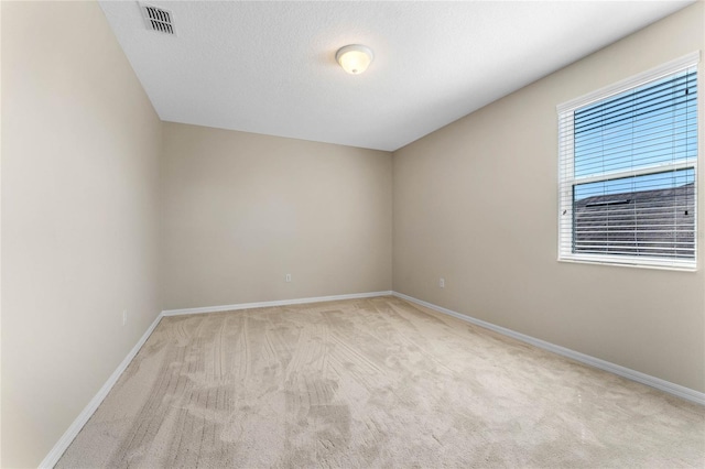 unfurnished room featuring a textured ceiling, baseboards, visible vents, and light carpet