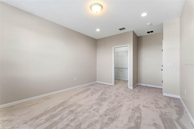 unfurnished bedroom featuring a closet, visible vents, a walk in closet, and baseboards