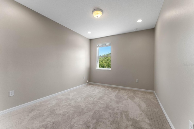 spare room featuring recessed lighting, baseboards, and light carpet