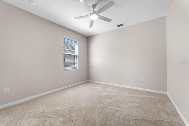 unfurnished room featuring a ceiling fan, visible vents, baseboards, a textured ceiling, and light colored carpet