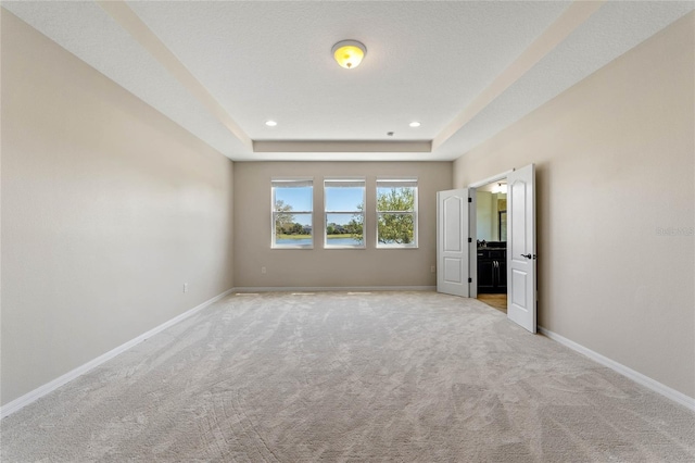 unfurnished bedroom with carpet flooring, recessed lighting, a raised ceiling, and baseboards