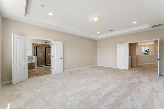 unfurnished bedroom featuring visible vents, a raised ceiling, and light carpet