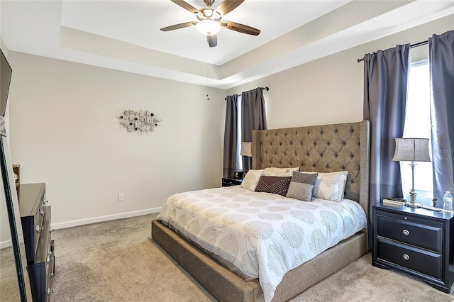 carpeted bedroom featuring a tray ceiling and ceiling fan