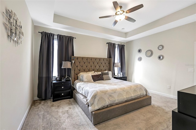 carpeted bedroom featuring a raised ceiling and ceiling fan