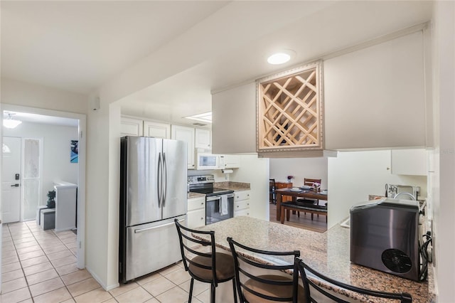 kitchen featuring stainless steel appliances, white cabinetry, and light tile patterned flooring