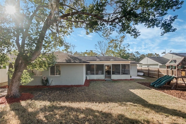 rear view of property with a yard, a playground, and a sunroom