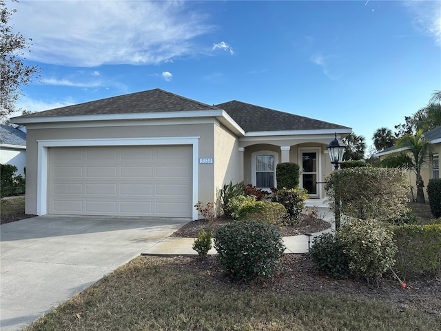 single story home with concrete driveway, roof with shingles, an attached garage, and stucco siding