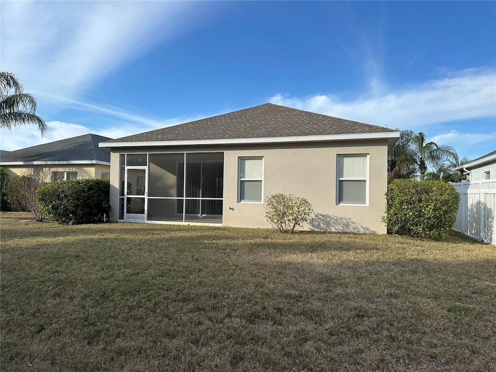 back of property featuring a sunroom and a lawn