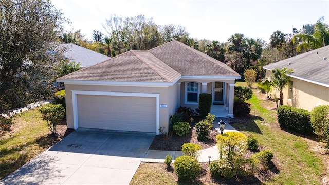 ranch-style home featuring stucco siding, a shingled roof, concrete driveway, an attached garage, and a front yard