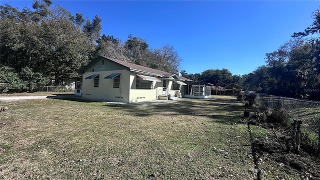 view of side of home featuring glass enclosure and a lawn