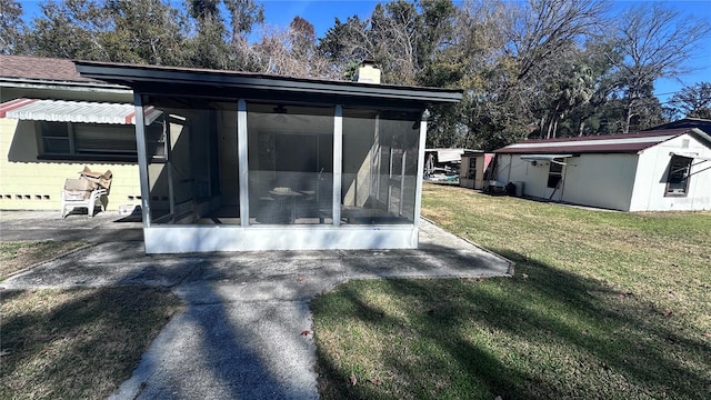 back of property featuring a yard, a patio area, and a sunroom