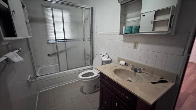 full bathroom with toilet, tile walls, vanity, enclosed tub / shower combo, and tile patterned flooring