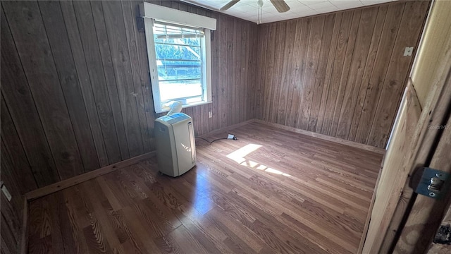 spare room featuring hardwood / wood-style flooring, ceiling fan, and wooden walls