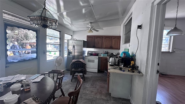 kitchen with electric stove, pendant lighting, ceiling fan with notable chandelier, and stainless steel refrigerator with ice dispenser