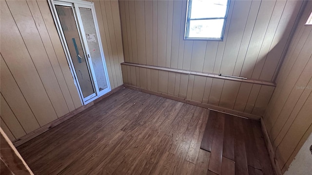 empty room featuring dark hardwood / wood-style flooring and wooden walls