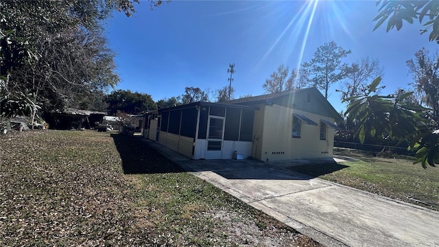 view of side of property with a sunroom and a lawn