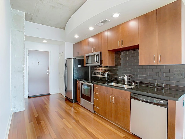 kitchen featuring stainless steel appliances, sink, light hardwood / wood-style floors, and decorative backsplash