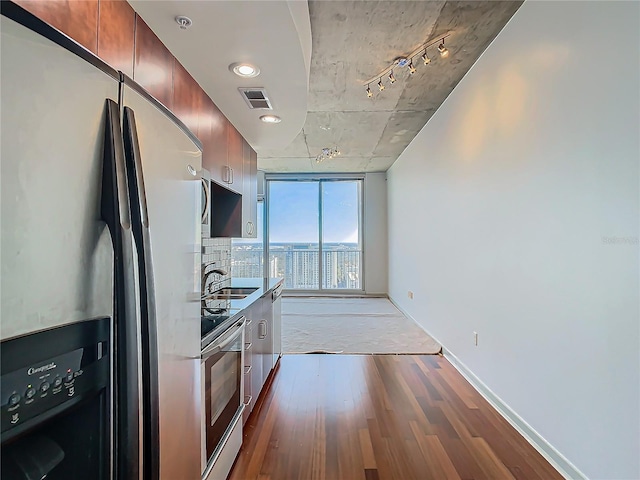 kitchen with stainless steel refrigerator with ice dispenser, sink, hardwood / wood-style floors, and wall oven