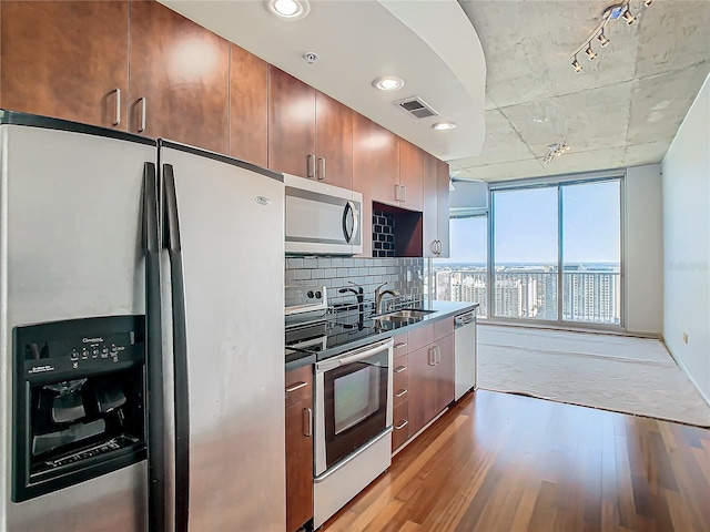 kitchen with appliances with stainless steel finishes, tasteful backsplash, sink, light hardwood / wood-style floors, and track lighting