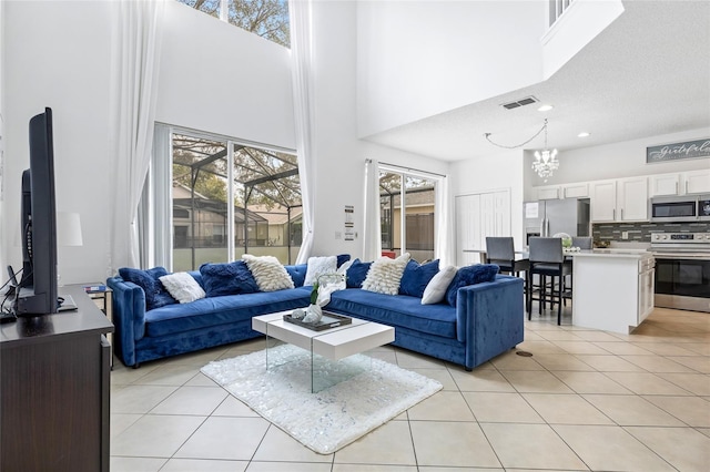 tiled living room with a high ceiling, a notable chandelier, and a textured ceiling