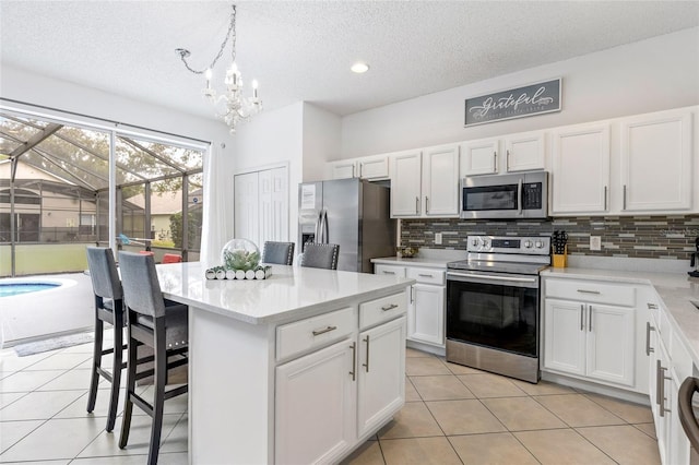 kitchen featuring pendant lighting, appliances with stainless steel finishes, white cabinetry, a kitchen breakfast bar, and a center island