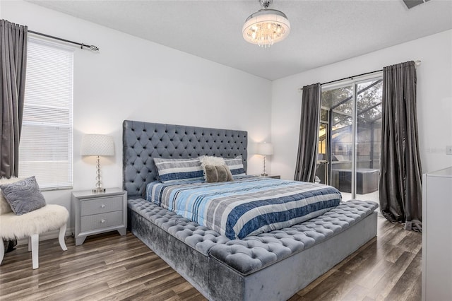 bedroom with dark hardwood / wood-style floors, an inviting chandelier, access to exterior, and a textured ceiling