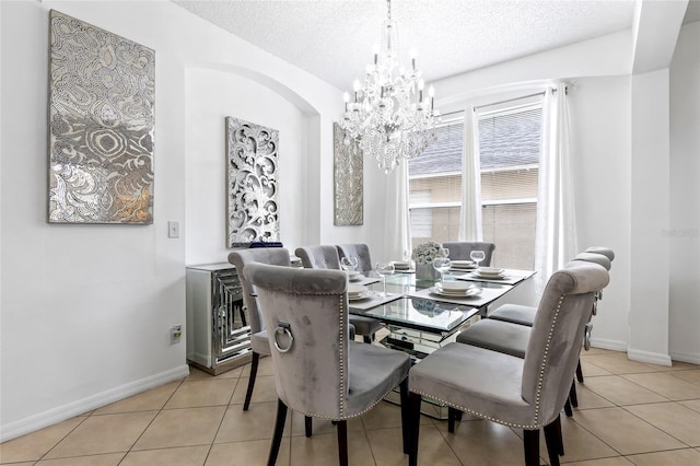 tiled dining area featuring a chandelier and a textured ceiling