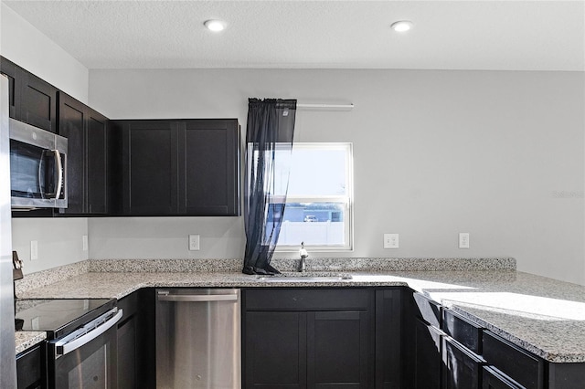 kitchen featuring light stone counters, sink, stainless steel appliances, and a textured ceiling