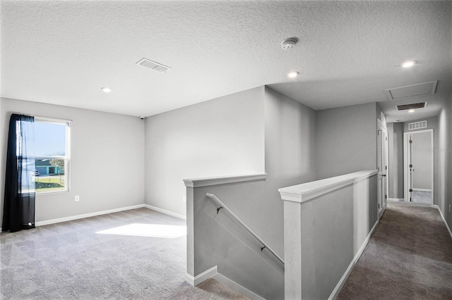 hallway with carpet floors and a textured ceiling