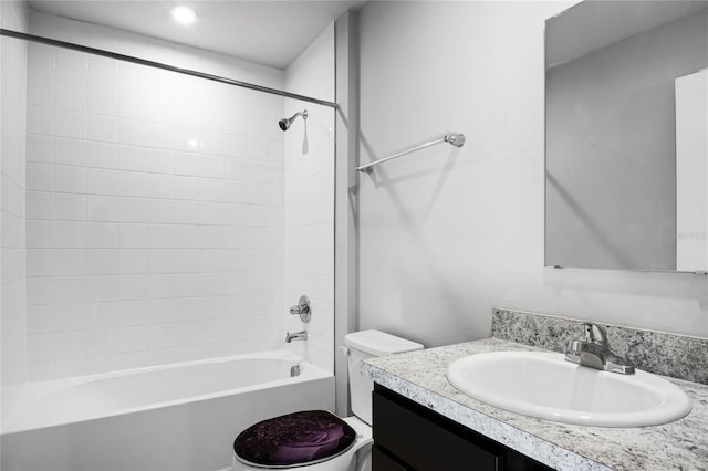 full bathroom featuring vanity, tiled shower / bath combo, and toilet