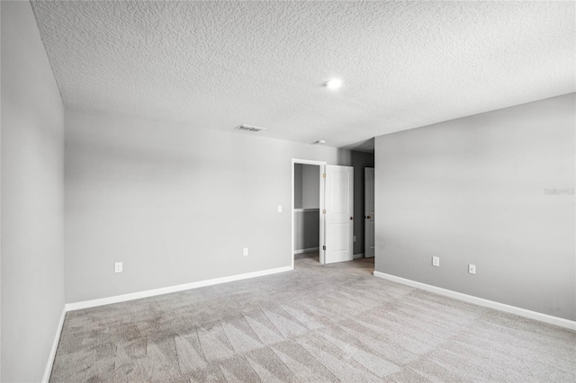 unfurnished bedroom featuring a spacious closet, light colored carpet, and a textured ceiling