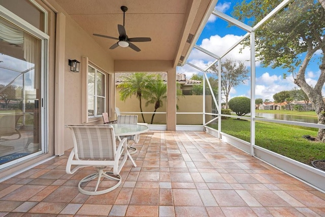 unfurnished sunroom featuring ceiling fan and a water view