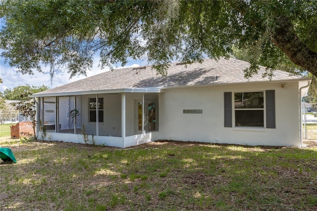 back of property with a sunroom and a lawn