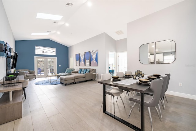 dining space featuring light hardwood / wood-style floors, a skylight, high vaulted ceiling, and french doors