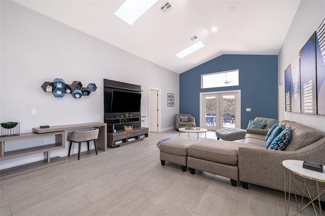 living room featuring high vaulted ceiling, a skylight, light hardwood / wood-style floors, and french doors