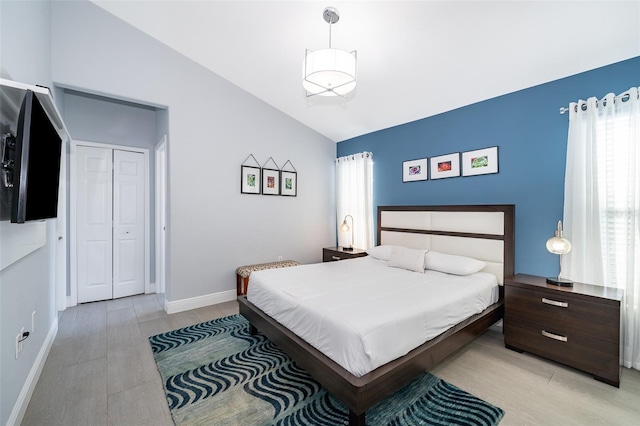 bedroom with vaulted ceiling, light hardwood / wood-style floors, and a closet