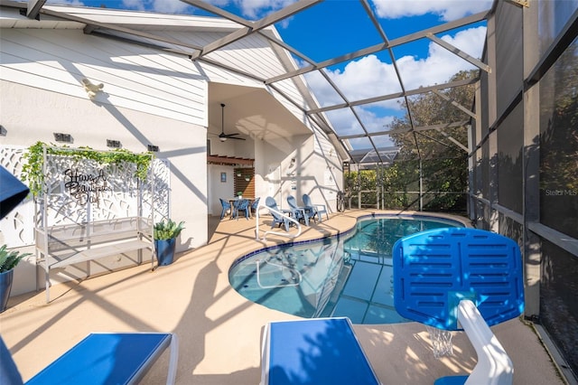 view of pool with ceiling fan, glass enclosure, and a patio area