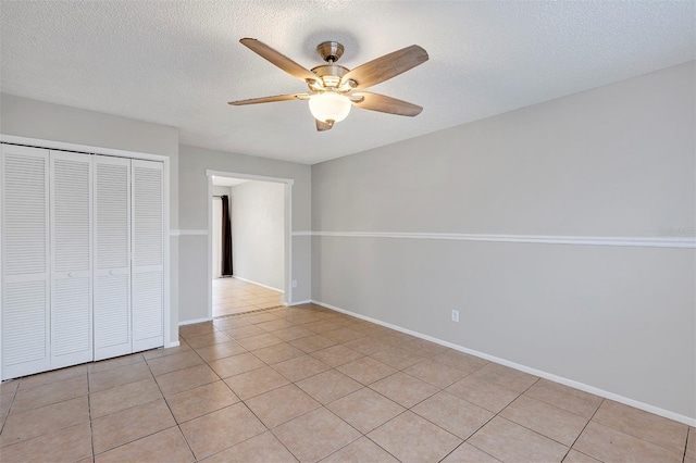 unfurnished bedroom with light tile patterned floors, ceiling fan, a closet, and a textured ceiling