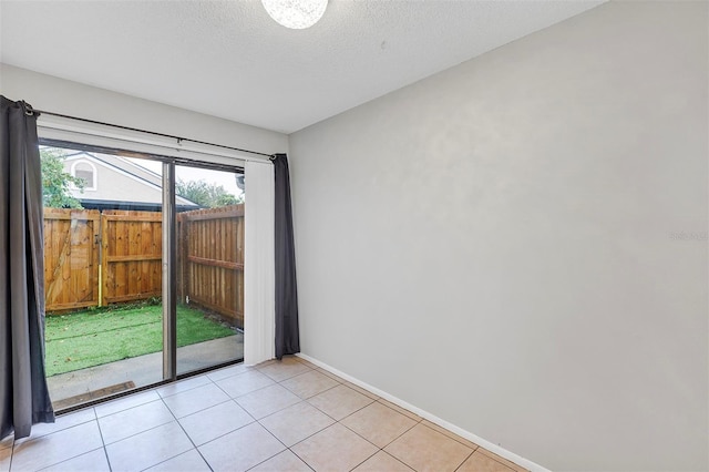 spare room featuring light tile patterned flooring, a textured ceiling, and baseboards