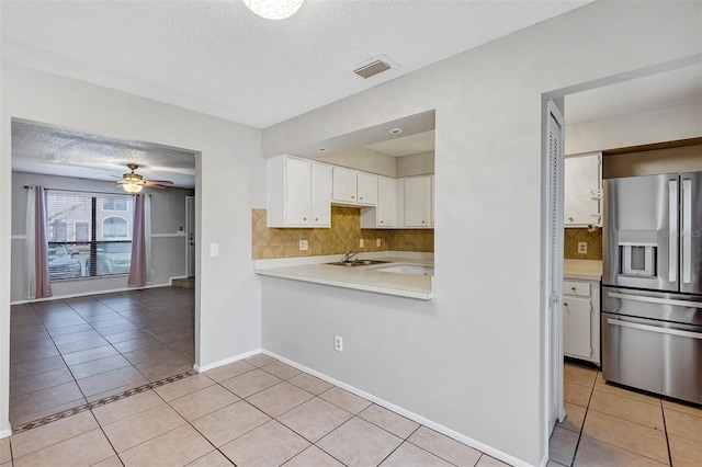 kitchen with light countertops, stainless steel fridge, visible vents, and light tile patterned flooring