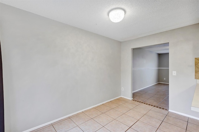 unfurnished room with a textured ceiling, light tile patterned flooring, and baseboards